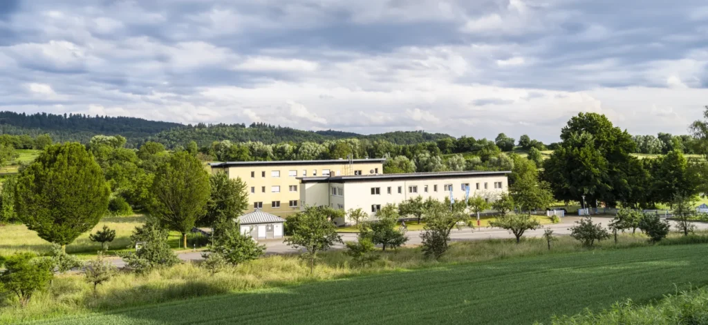 Blick von weitem über grüne Landschaft auf die Klinik